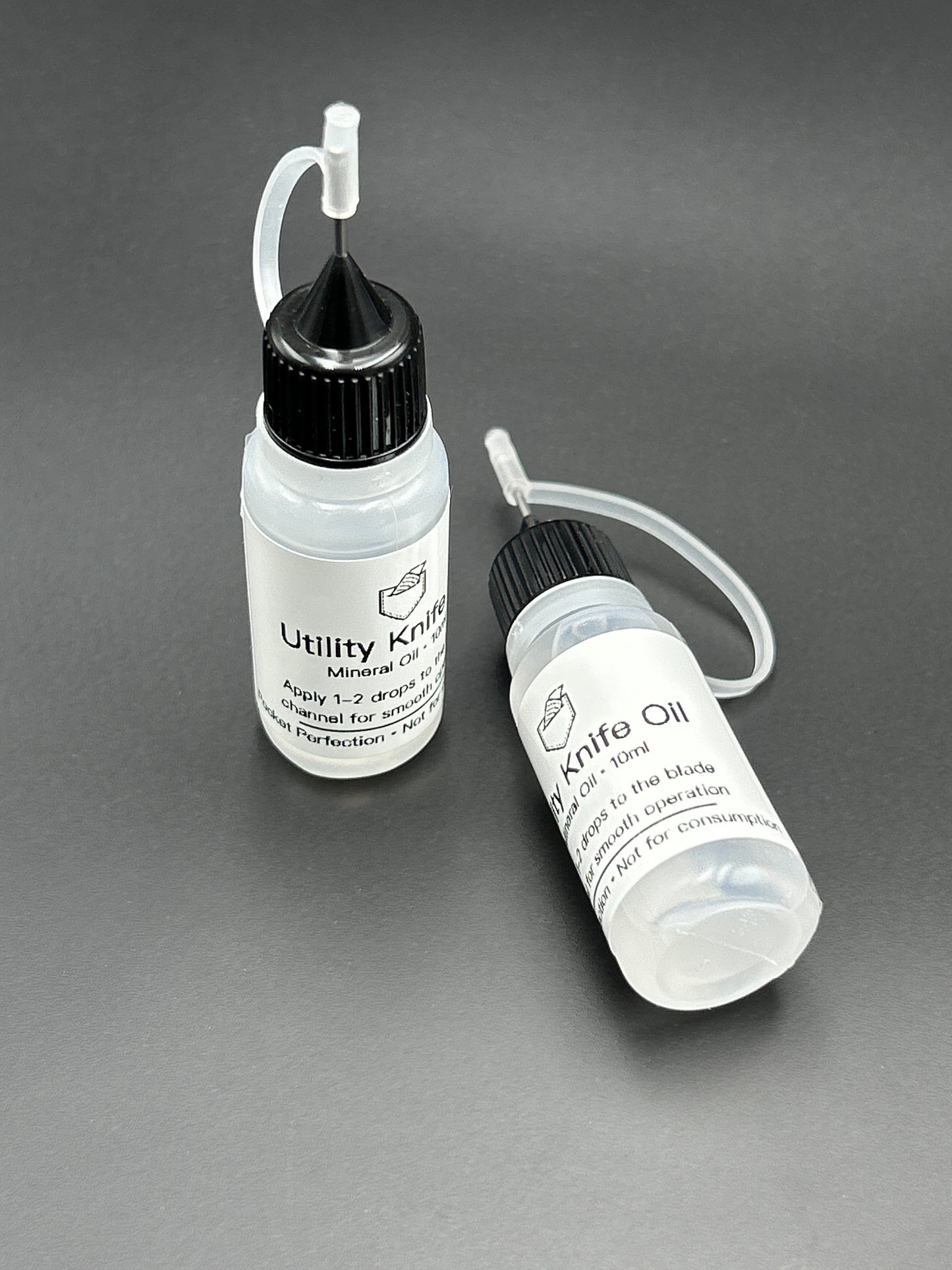 Two small bottles labeled 'Knife Oil' on a gray background