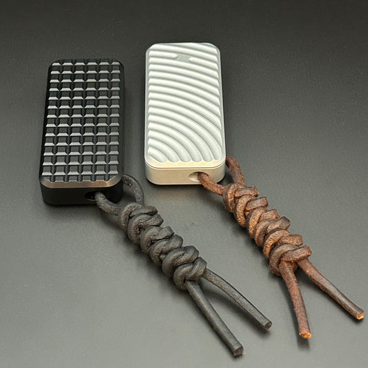 Black and brown leather lanyards tied to Rivery Zero Knives, with blades retracted