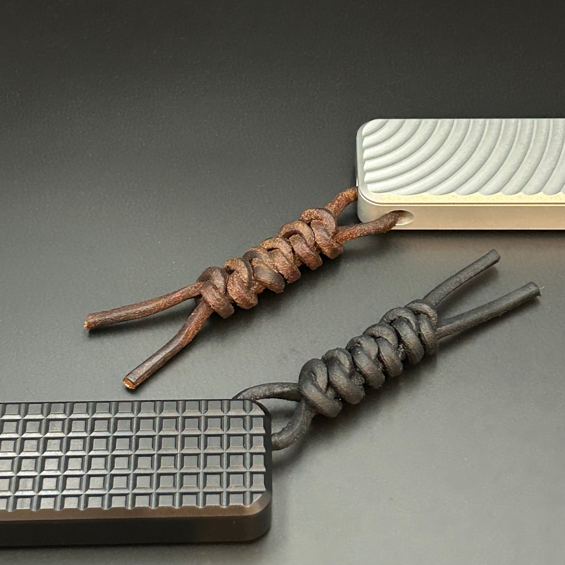 Black and brown leather lanyards tied to Rivery Zero Knives, with blades retracted