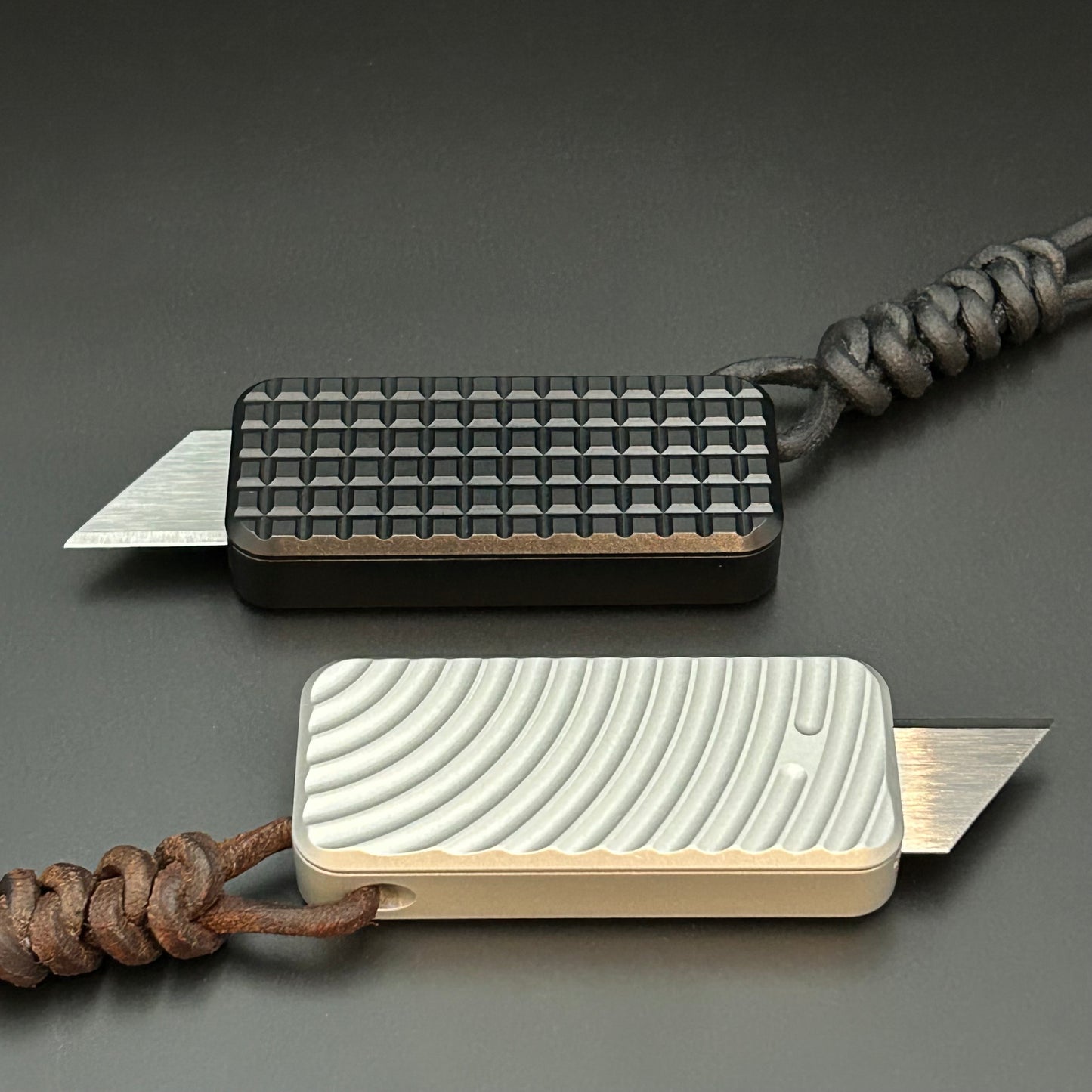 Black and brown leather lanyards tied to Rivery Zero Knives, with blades exposed