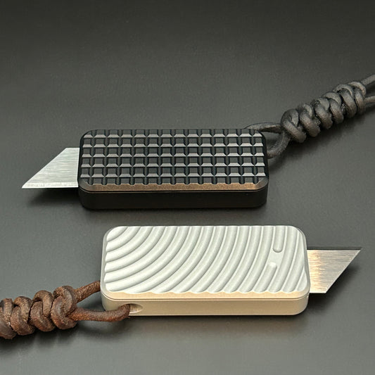 Black and brown leather lanyards tied to Rivery Zero Knives, with blades exposed