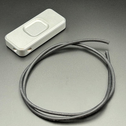 Black leather lanyard coiled in a loop, situated next to a Rivery Zero knife