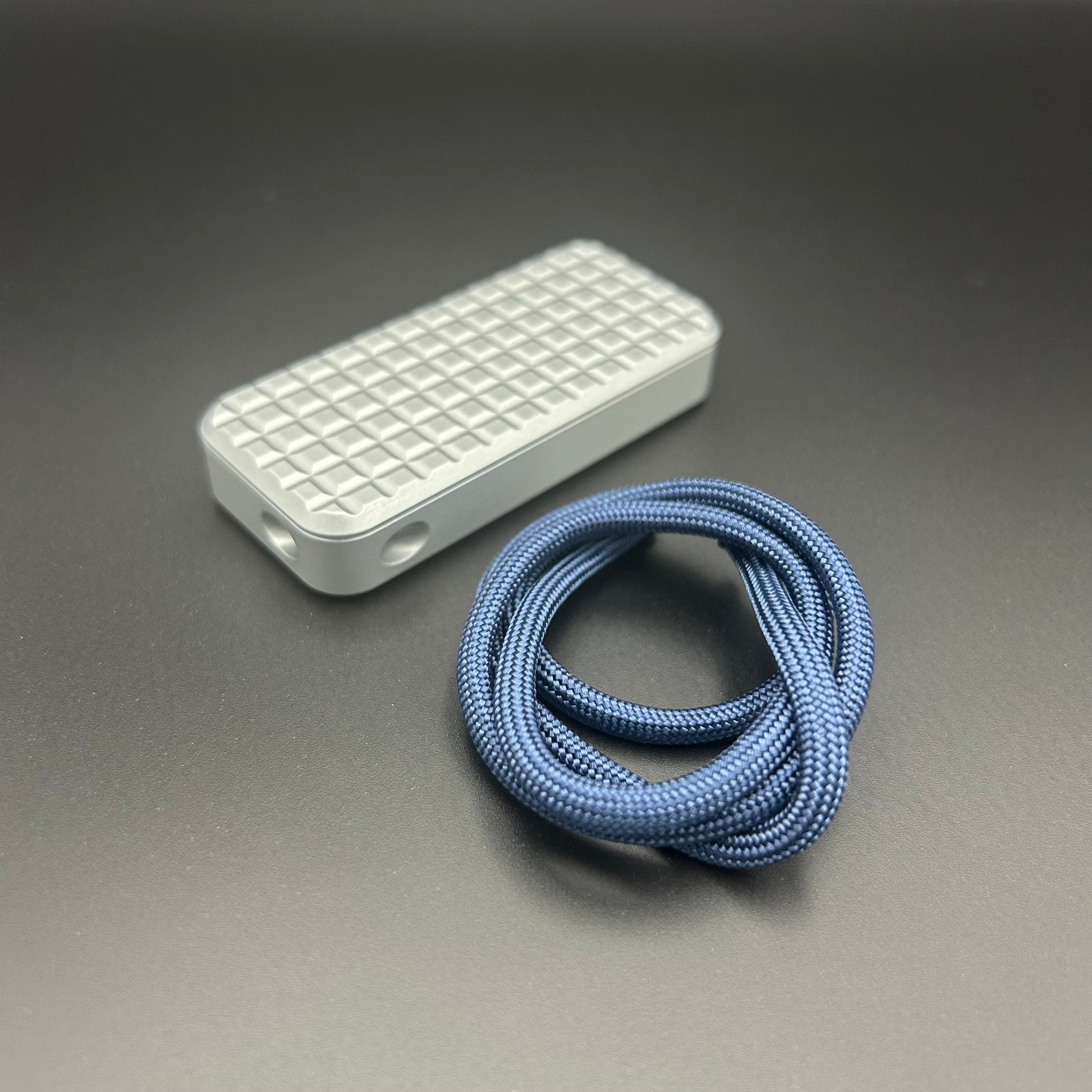 Blue paracord lanyard coiled in a loop, situated next to a Rivery Zero knife