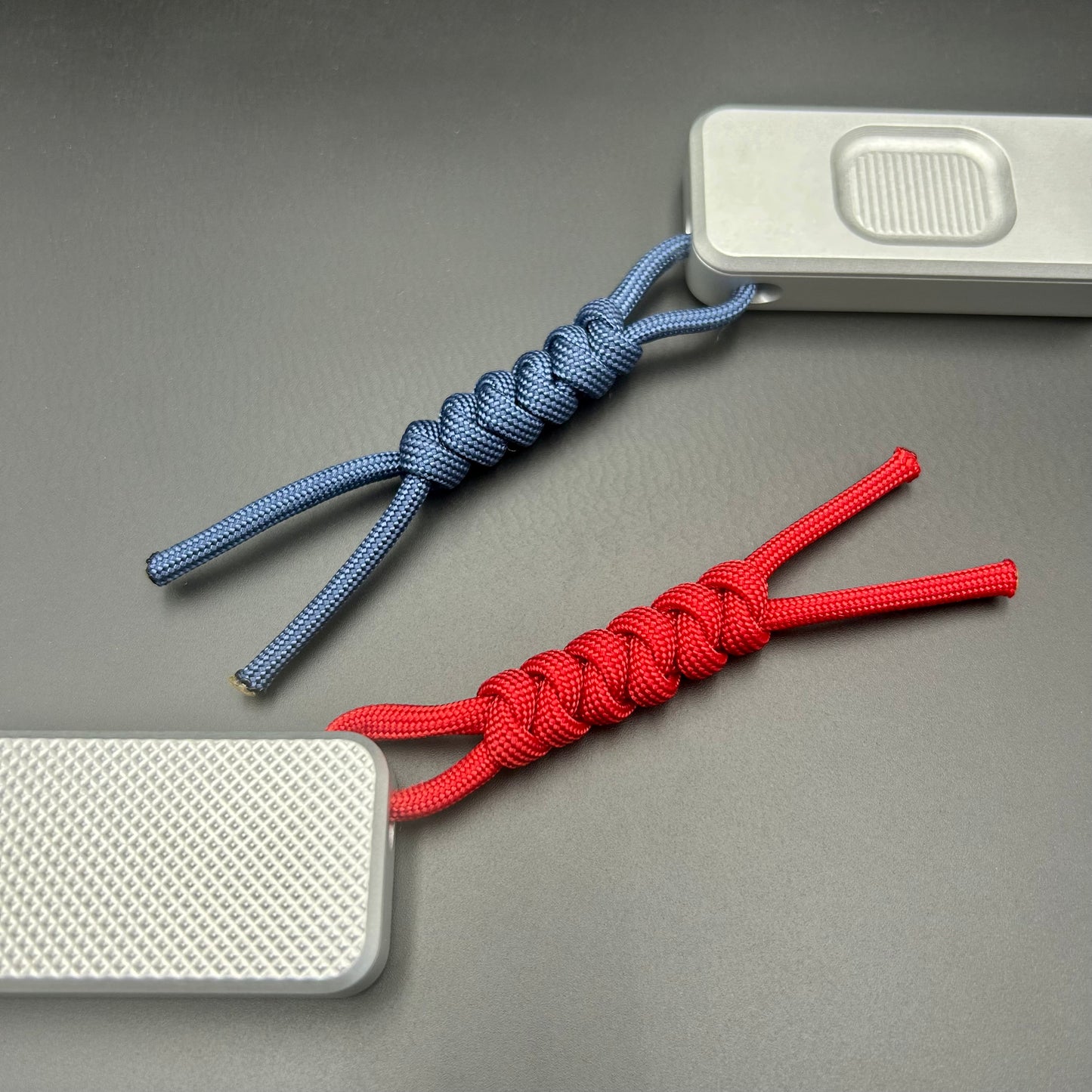 Blue and red paracord lanyards tied to Rivery Zero Knives, with blades retracted