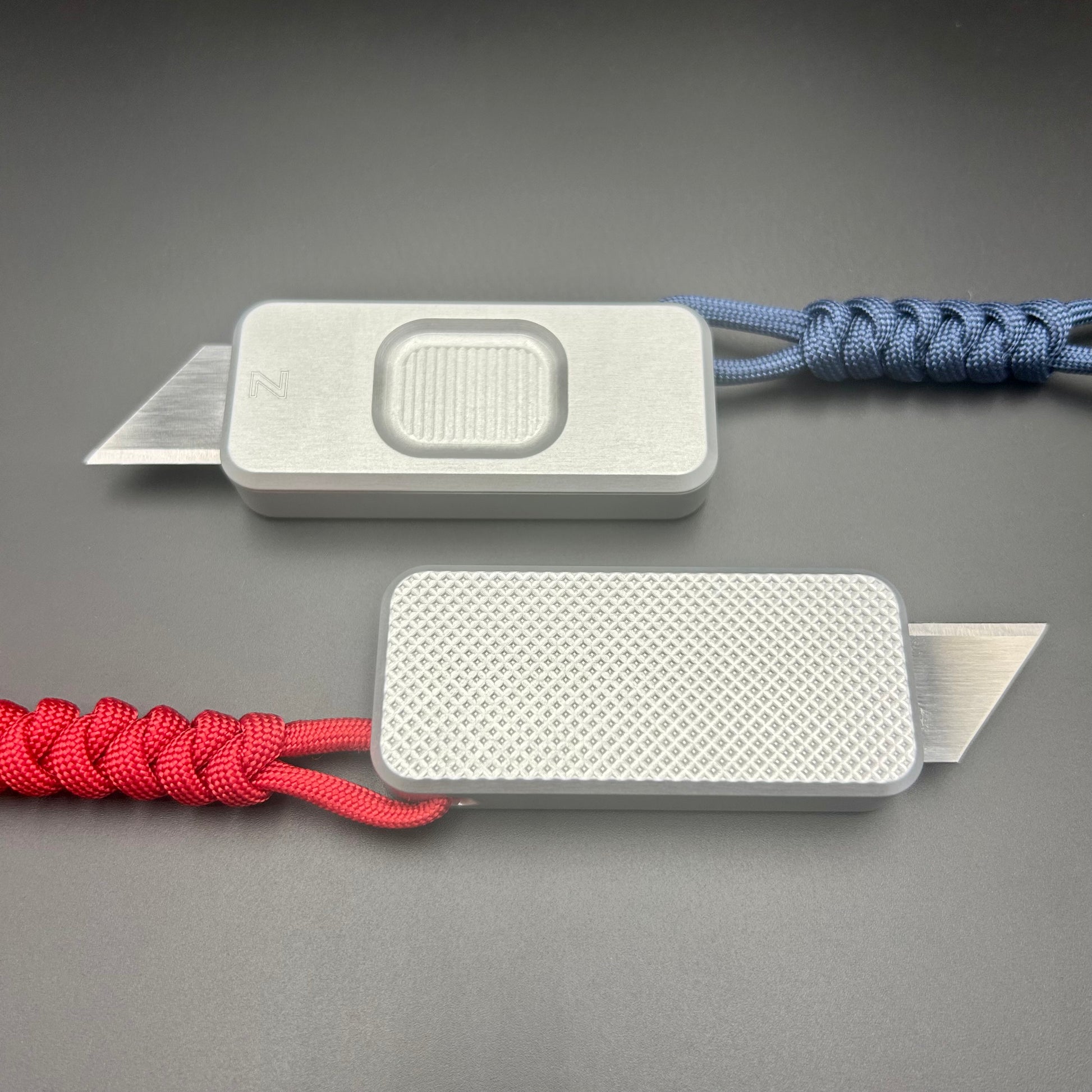 Blue and red paracord lanyards tied to Rivery Zero Knives, with blades exposed