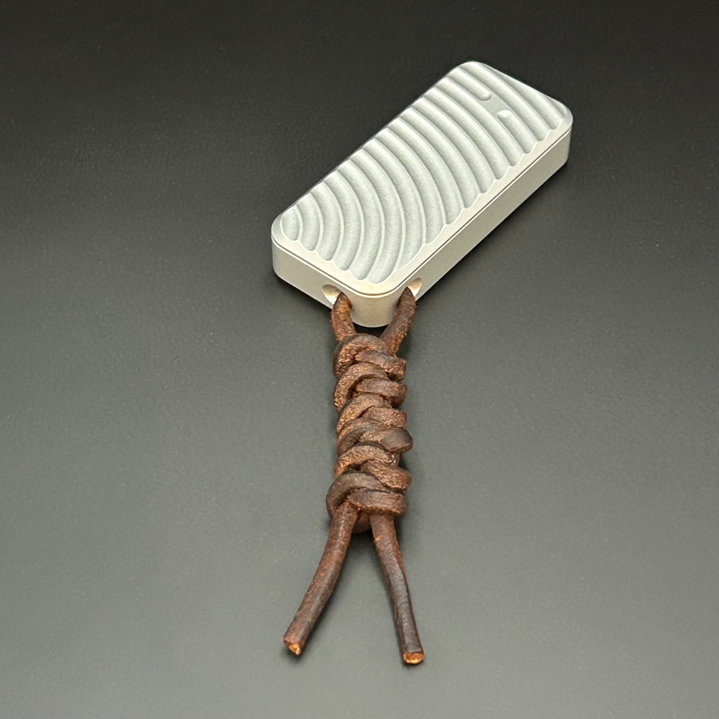 Brown leather lanyard tied to Rivery Zero Knife, with blade retracted