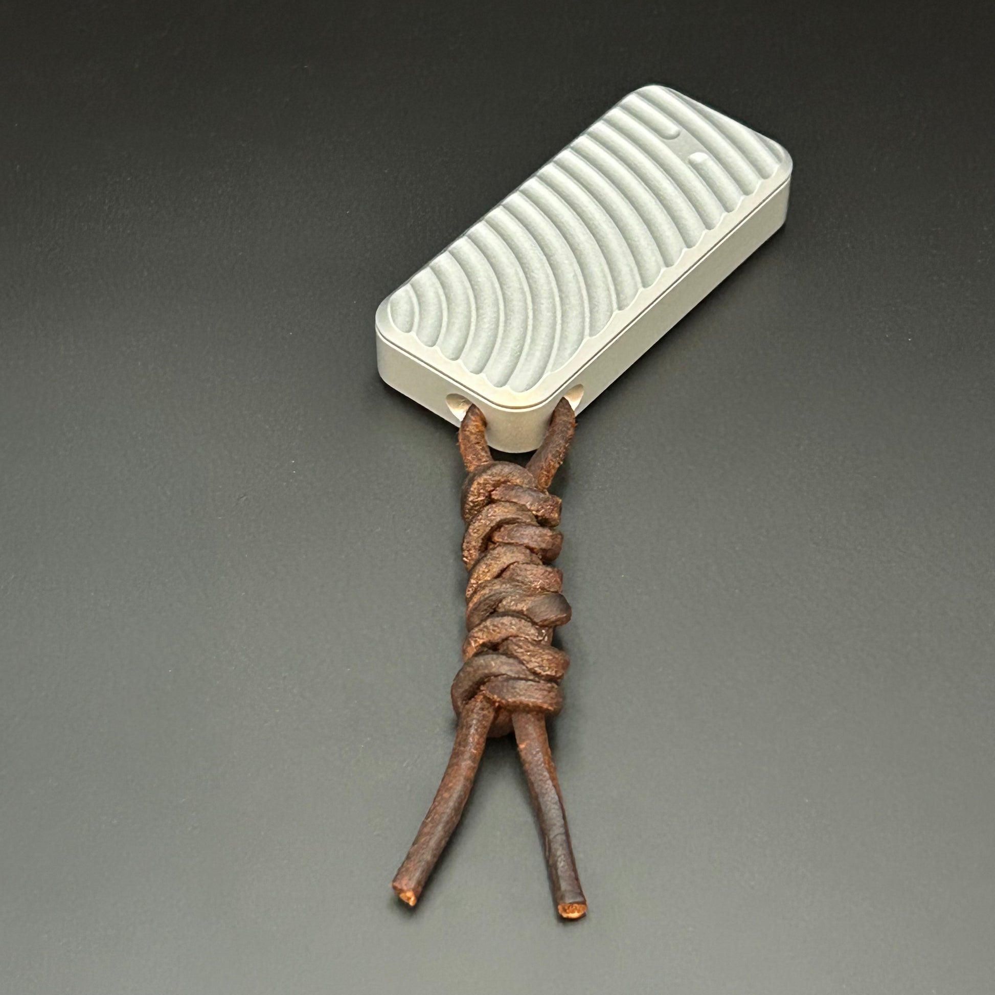 Brown leather lanyard tied to Rivery Zero Knife, with blade retracted