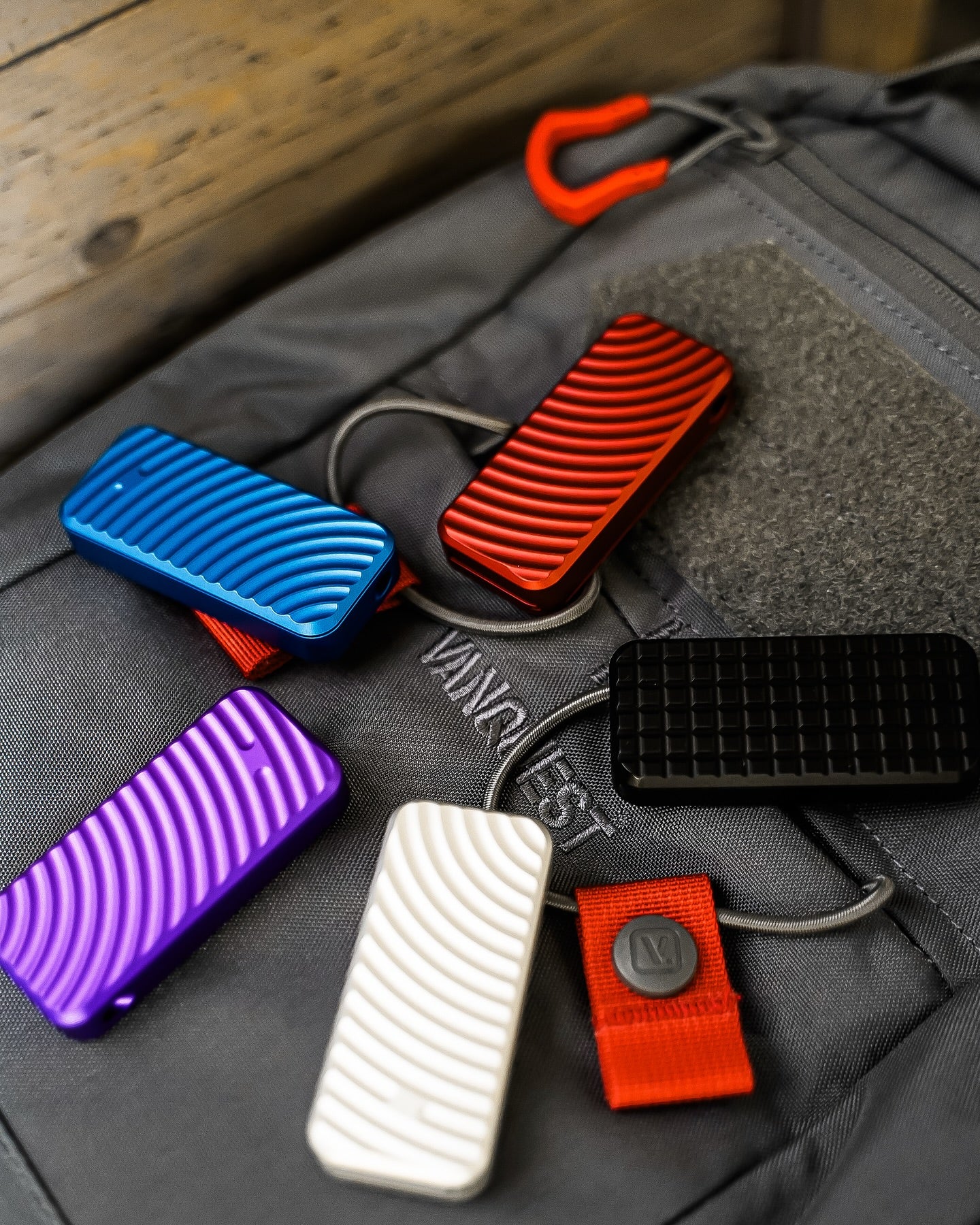 Five Zero knives displayed in a circle with blades retracted, shown in blue, purple, silver, black and red