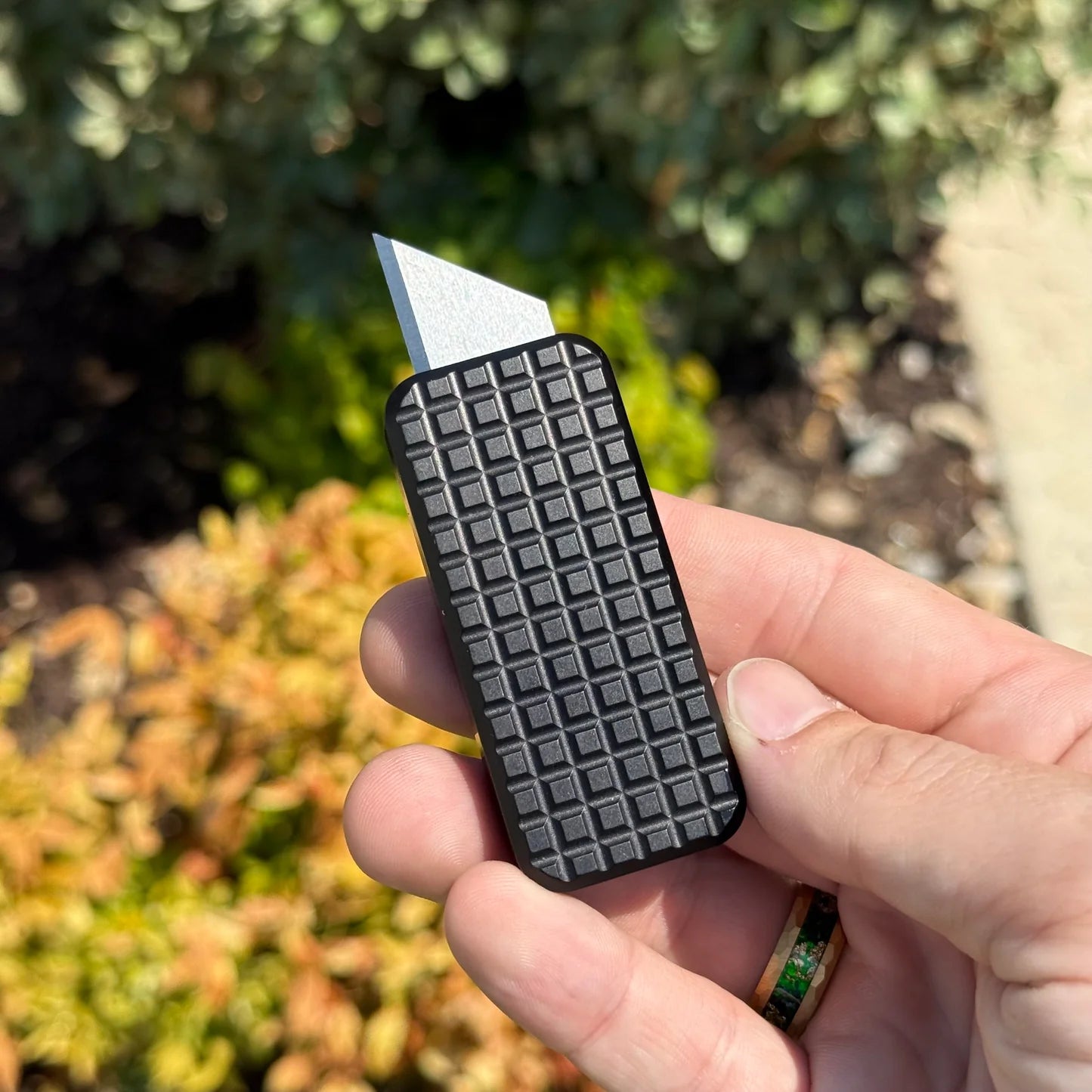 Zero knife with Black Grenade Pattern and blade extended, being held in a hand