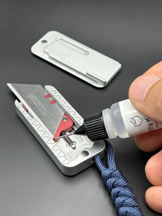 Zero Knife with a blue paracord being lubricated with a bottle of oil.