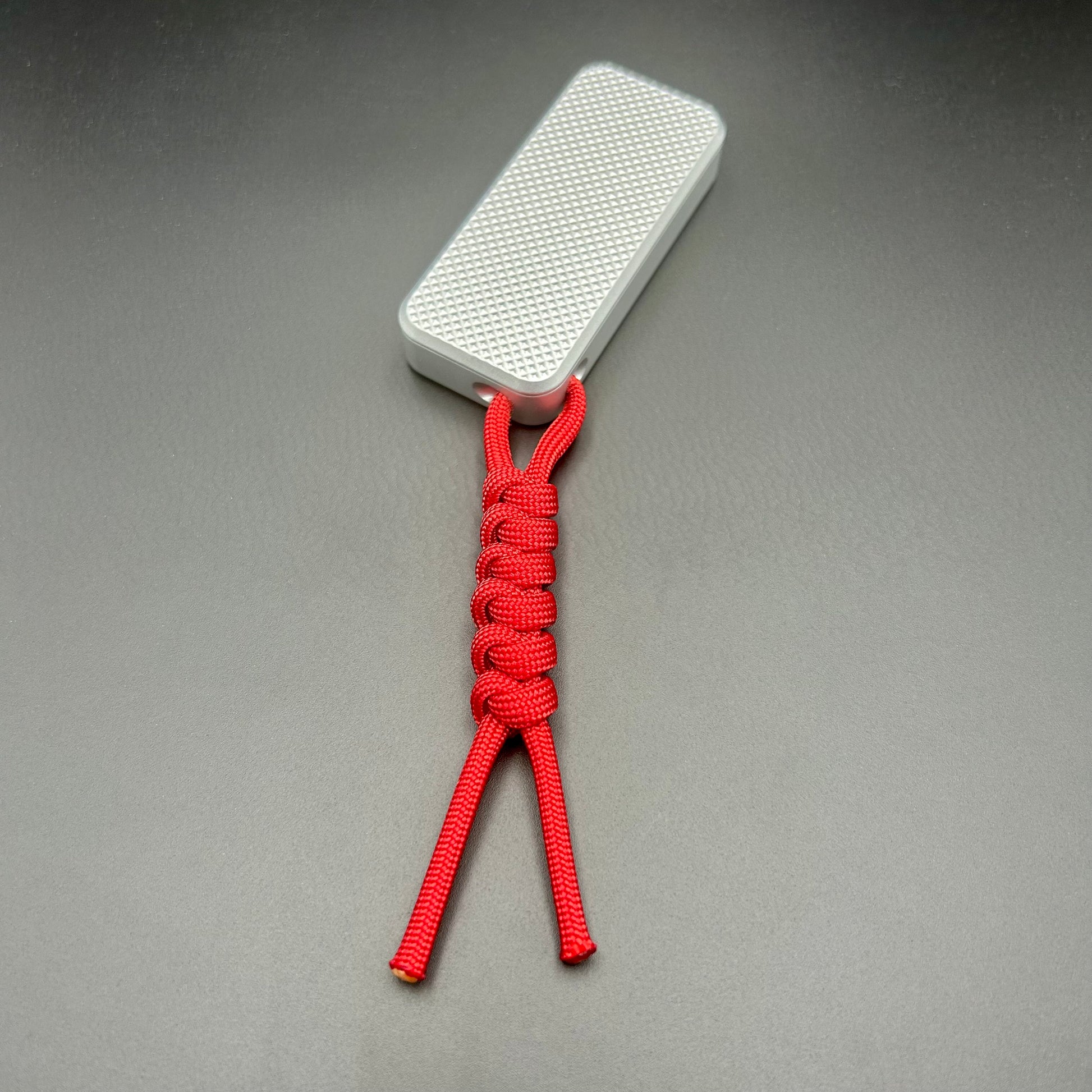 Red paracord lanyard tied to Rivery Zero Knife, with blade retracted