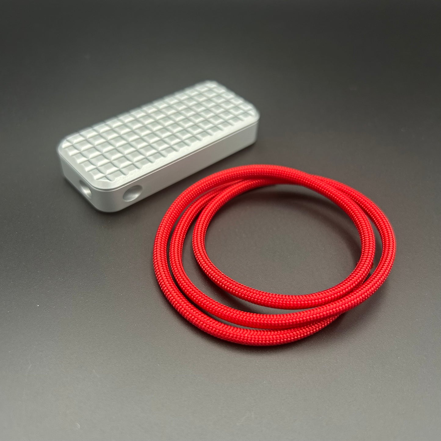 Red paracord lanyard coiled in a loop, situated next to a Rivery Zero knife