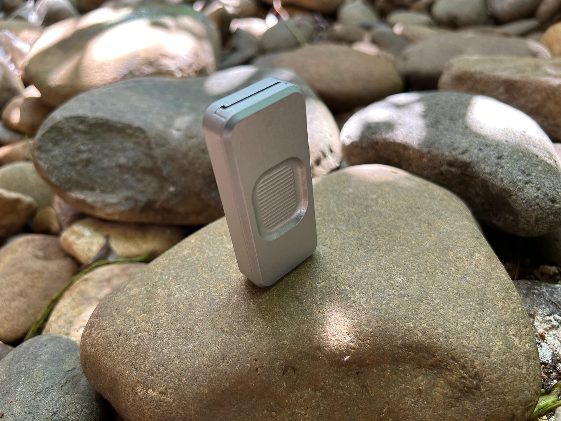 Rivery Zero knife with Smooth Operator finish and blade retracted, standing upright on a background of rocks