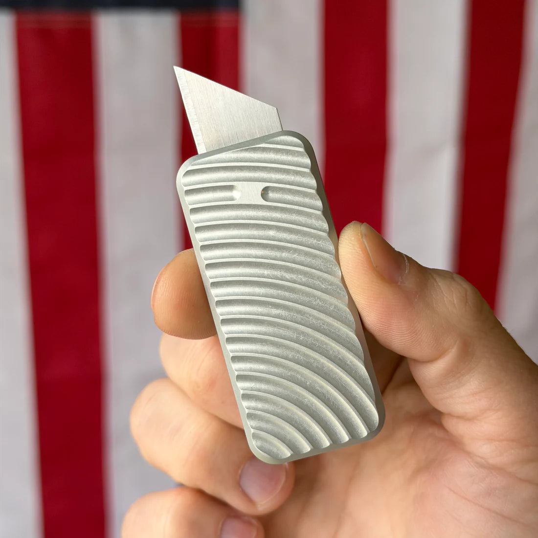 Hand holding a textured Zero knife with an American flag in the background